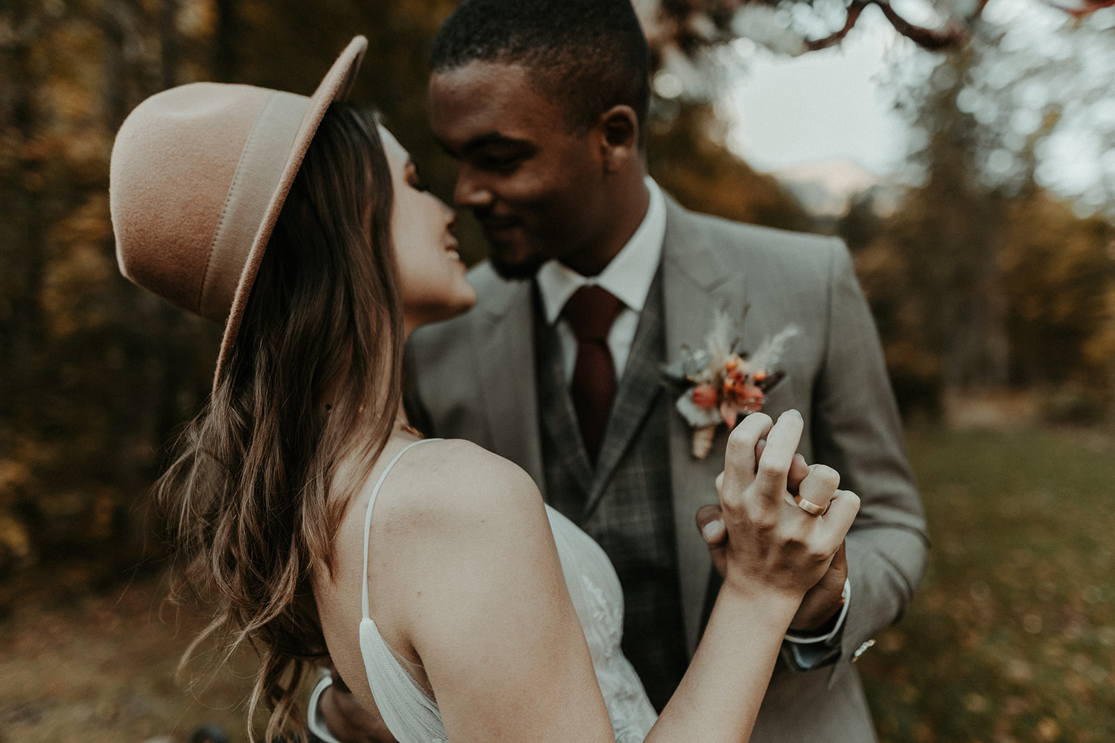 Ein Paar in Hochzeitskleidung tanzt eng umschlungen, lächelnd und händchenhaltend in einer Waldlandschaft während ihres Hochzeitswochenendes in der schönen Bodensee-Region, Schweiz.