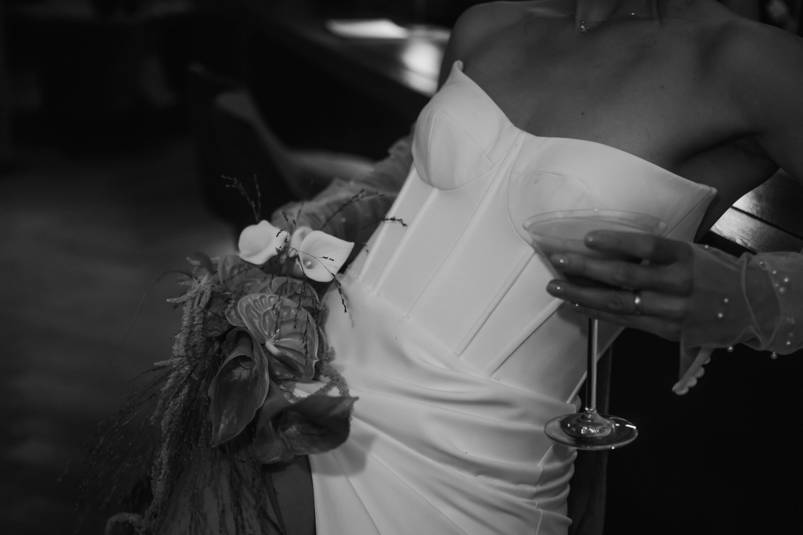 A woman in a strapless dress holds a cocktail and a bouquet of flowers in her hand, photographed in elegant black and white - capturing the chic spirit of the Lake Constance region.