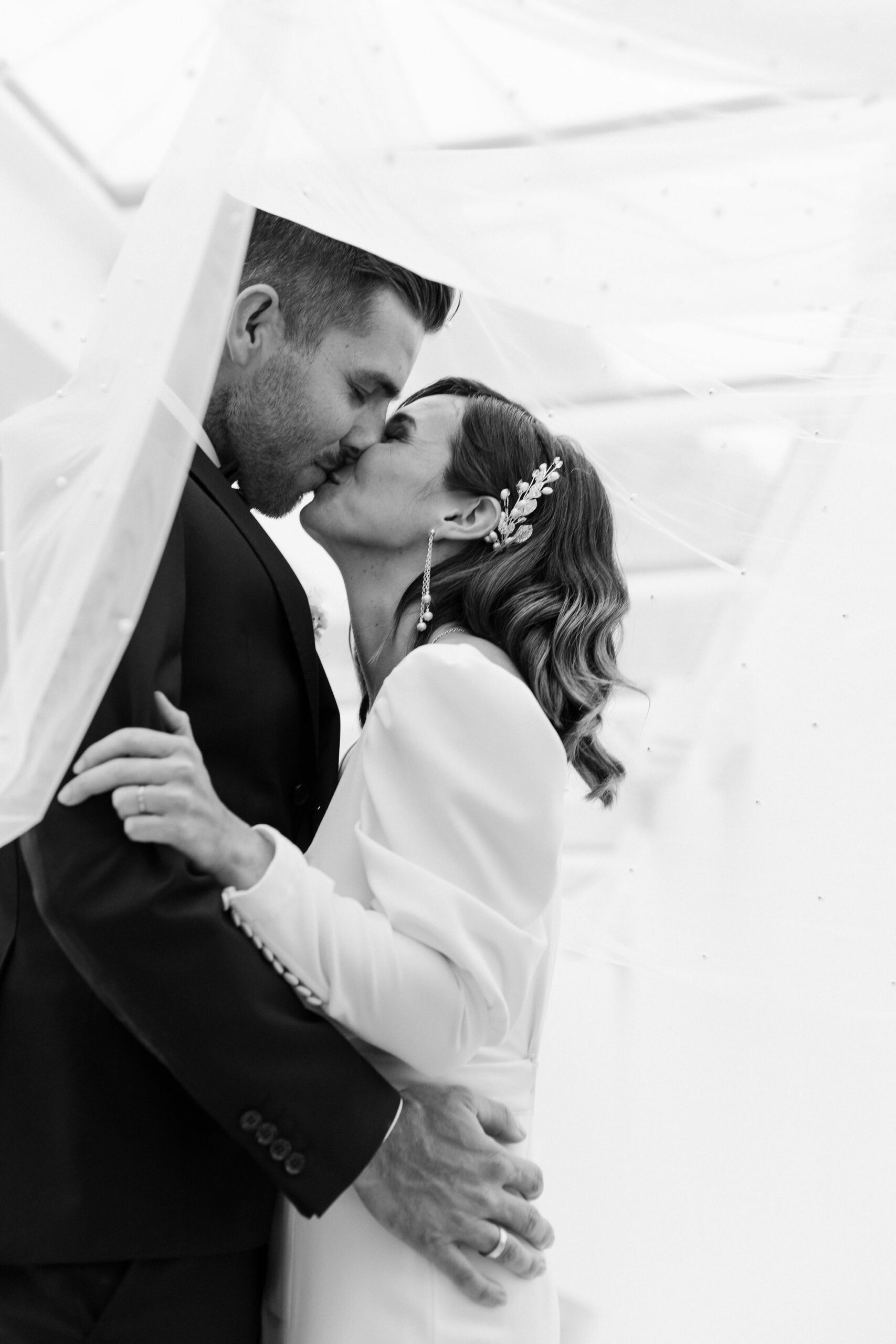 Bride and groom kiss under a veil and embrace on their wedding day in the picturesque Lake Constance region.