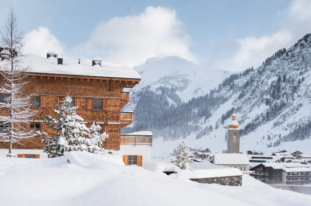 Snow-covered Alpine village with wooden hut, church tower and mountains in the background - perfect for a romantic wedding weekend in South Tyrol.