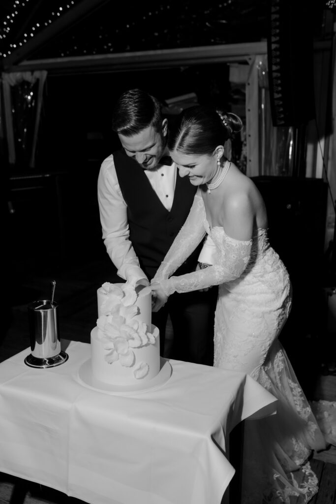 Braut und Bräutigam schneiden lächelnd ihre Hochzeitstorte an einem Hochzeitswochenende in der schönen Bodensee-Region an.