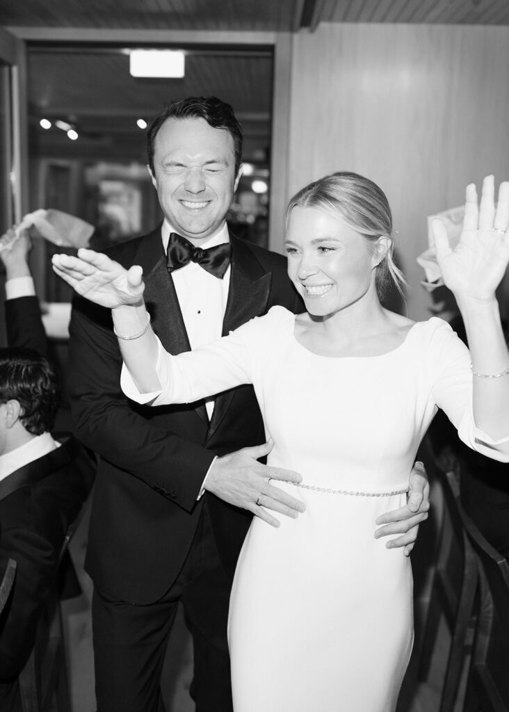 A smiling, formally dressed couple dance together and wave at a celebration in the picturesque Lake Constance region.