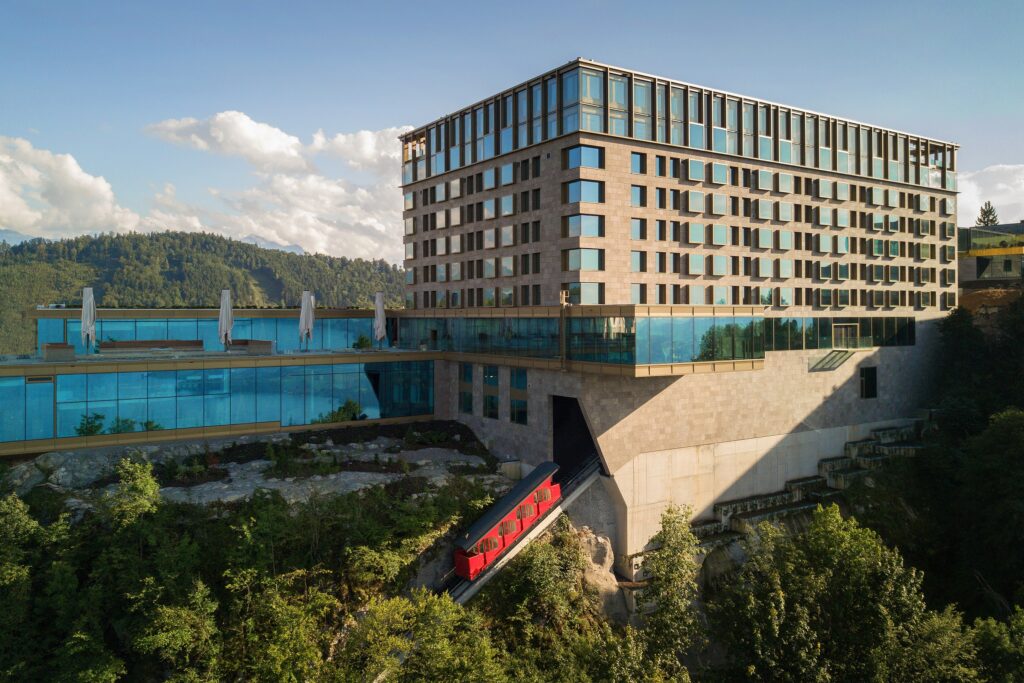 A modern hotel with large windows stands on the slope and serves as an elegant wedding venue (Bürgenstock).