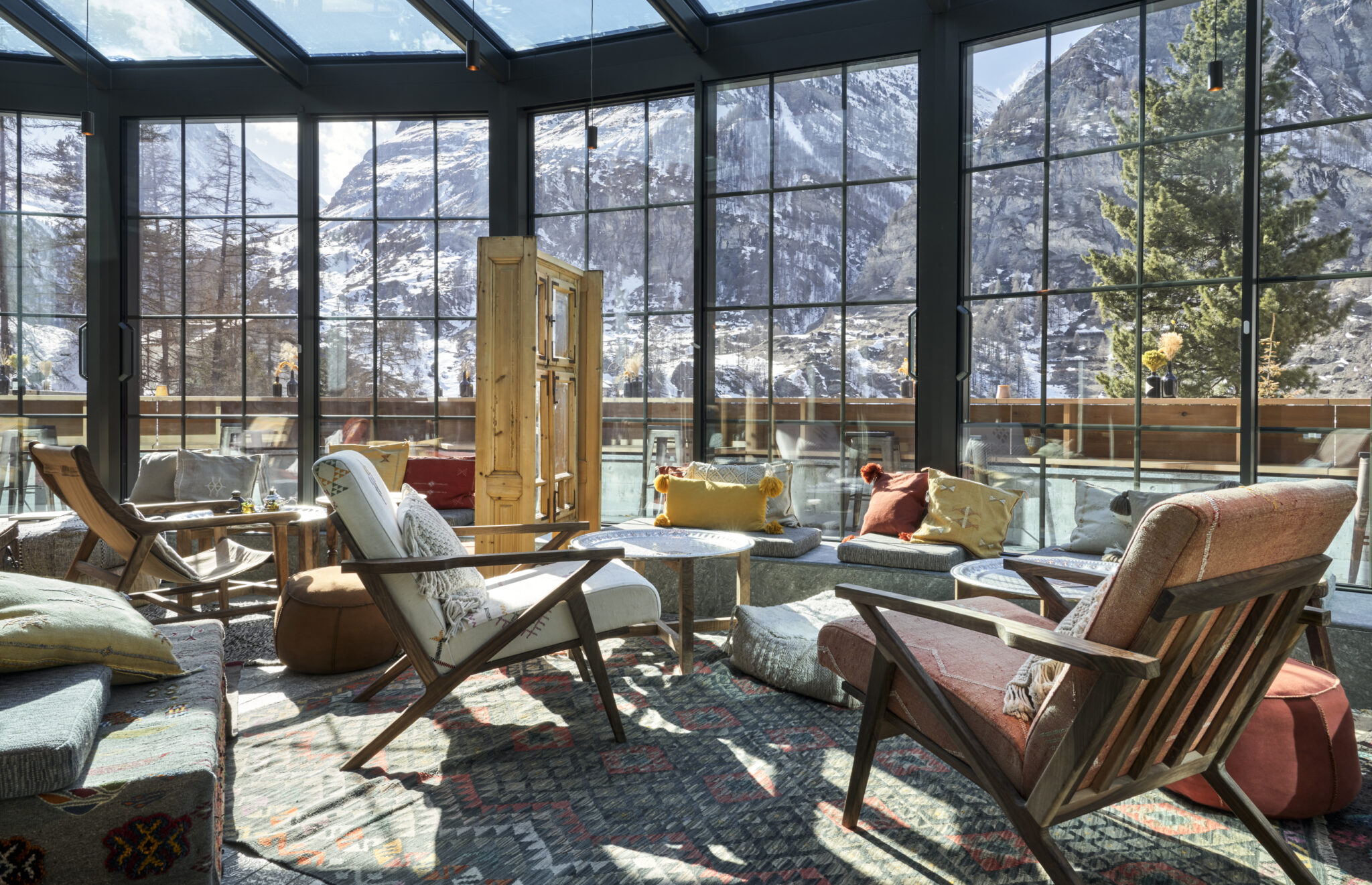 Cozy lounge with armchairs and large windows overlooking snow-covered mountains and trees, reminiscent of the serene alpine landscape in South Tyrol.